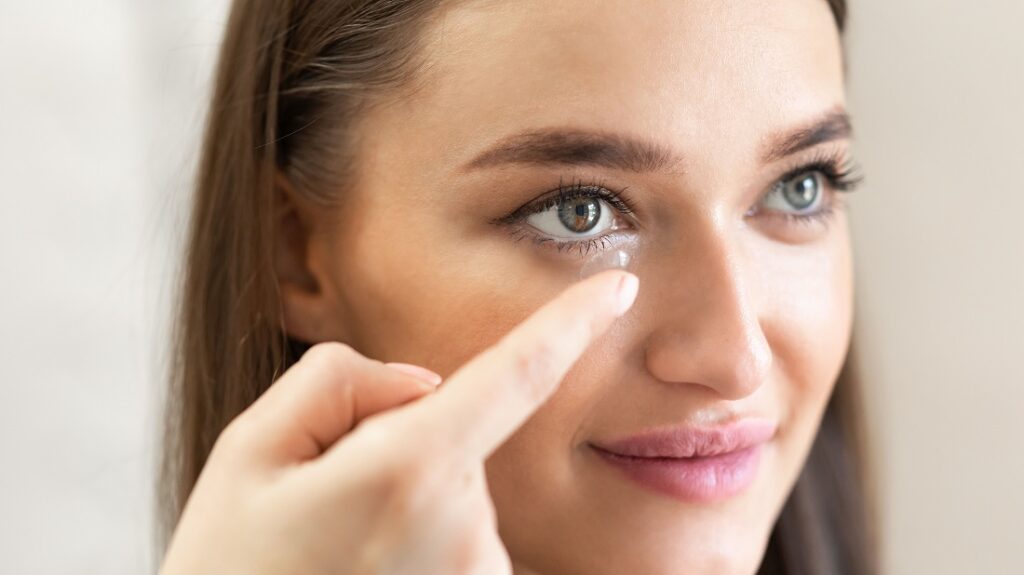 Beauty, Vision And Eyesight Concept. Closeup portrait of smiling lady applying soft eye lens. Happy woman inserting and trying on contacts for vision and eyesignt, holding it on finger, banner